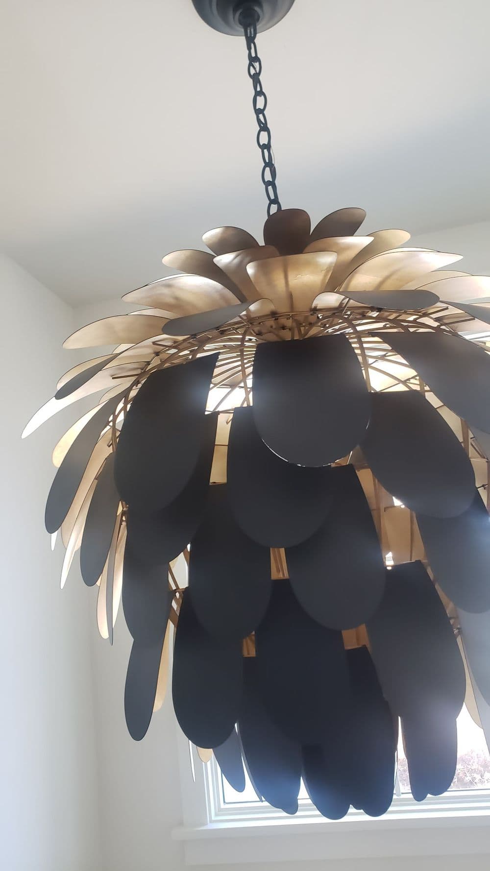 Elegant black and gold chandelier with petal-shaped design in a bright interior setting.
