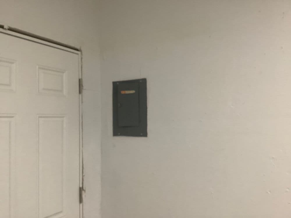 Electrical panel mounted on a white wall next to a closed door.